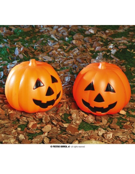 Due zucche luminose arancioni con volti intagliati su foglie autunnali per decorazioni Halloween